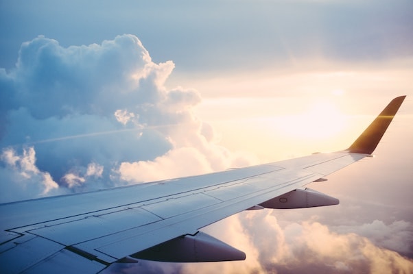 an airplane wing against a cloudy morning sky